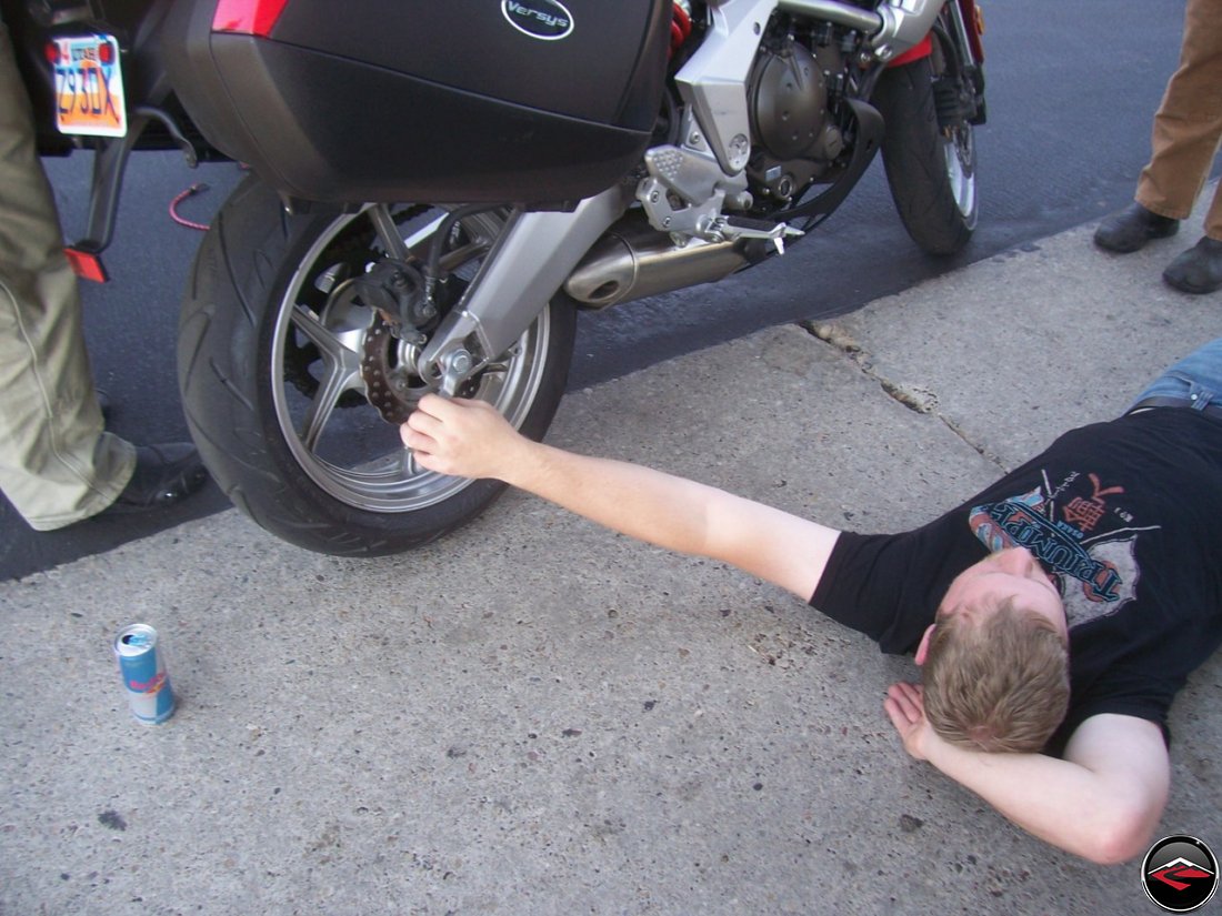 Man adjusting motorcycle chain on a Kawasaki Versys