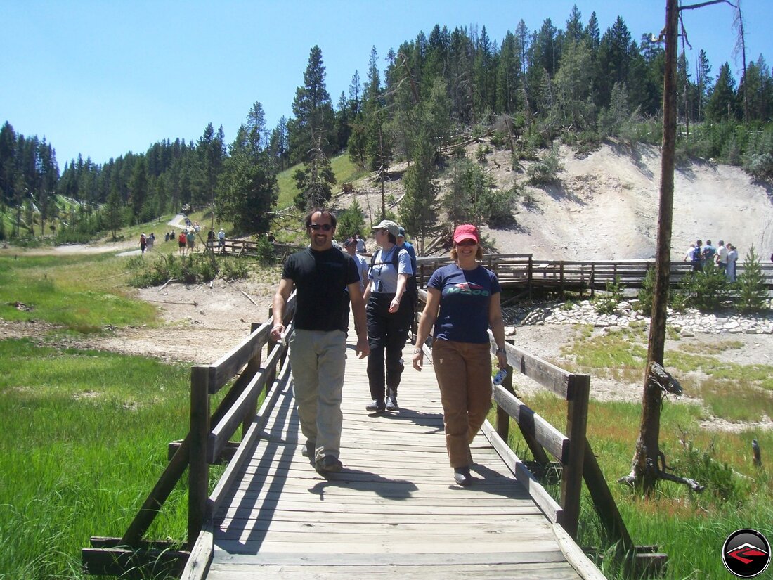 Group of people walking on wooden boardwalks around a yellowstone national park stink pot