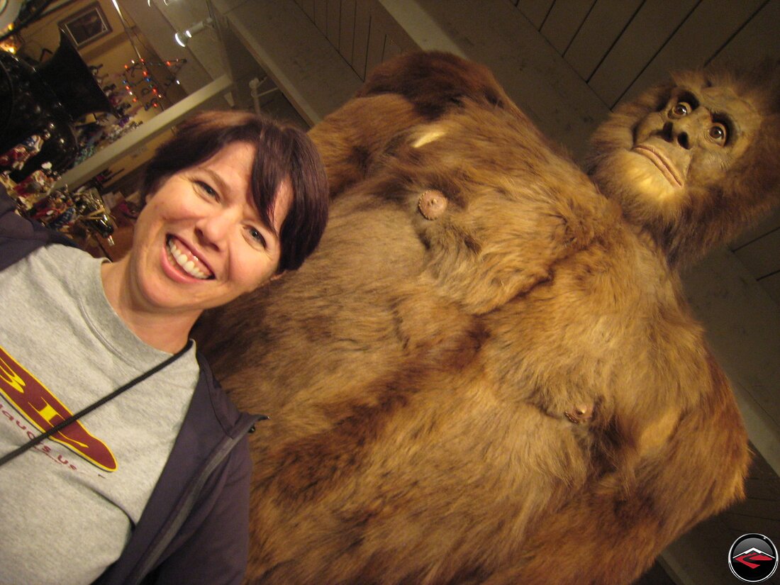 Woman standing in front of a stuffed big foot Sasquatch with plastic nipples in Jackson Hole, Wyoming