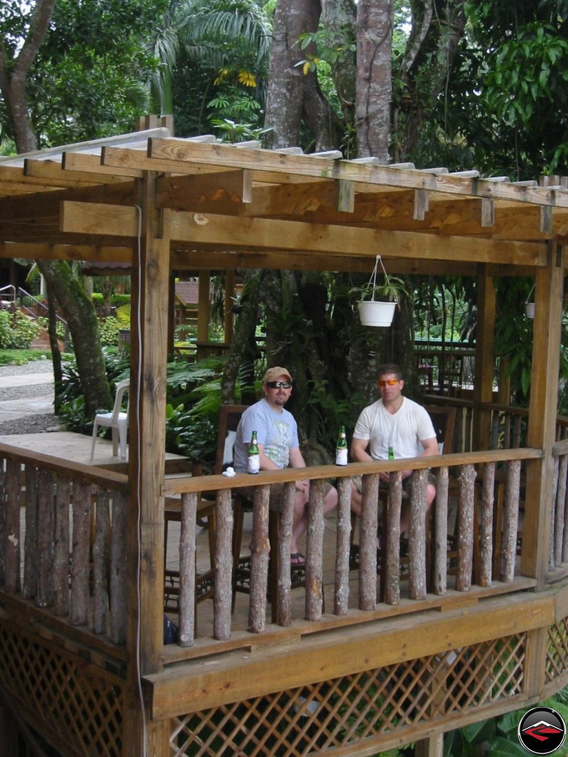 Two men drink beer on a patio