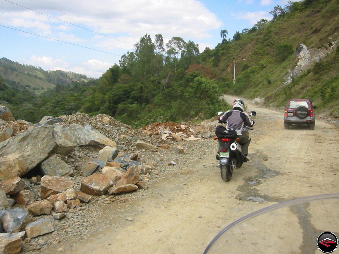 motorcycle navigating a gravel washout on a mountain road