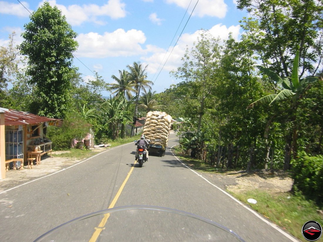 Motorcycle behind a truck with a dangerous load of bags