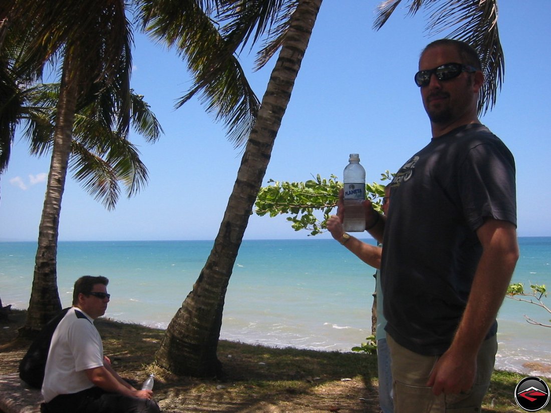 Man standing on the beach drinking bottled water