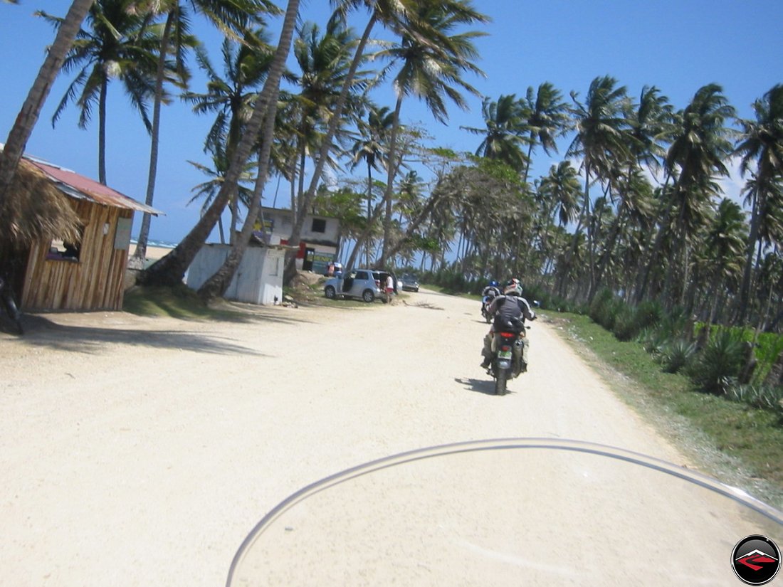 riding along the coast with palm trees and beach shacks