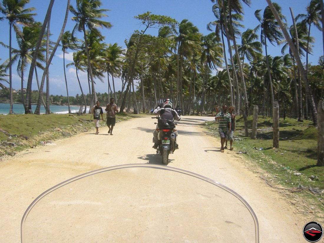 motorcycle riding down a Beautiful Caribbean coastal road with palm tree's and the atlantic ocean