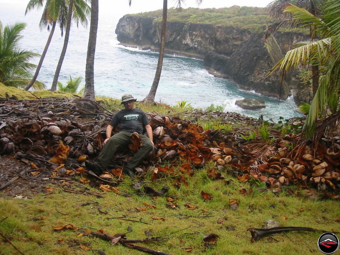 Man pretending to have eaten a giant pile of coconuts