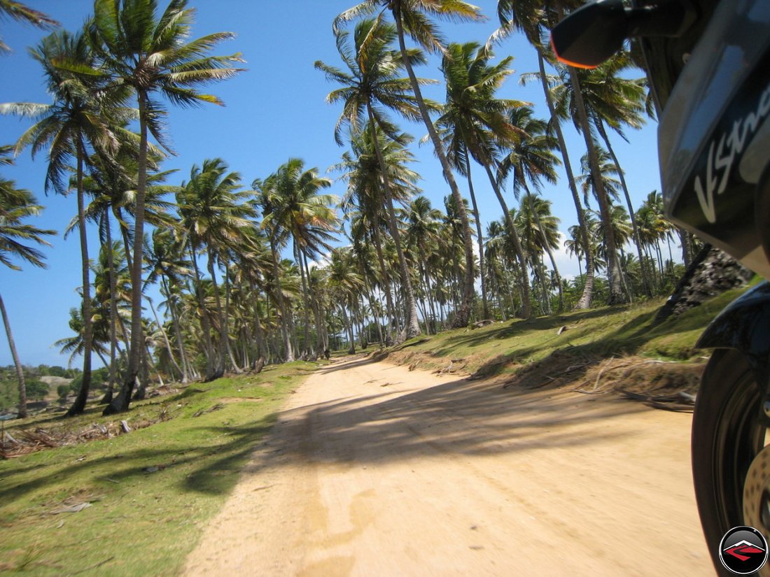 Motorcycle riding down a perfect sand road on a beach in the caribbean