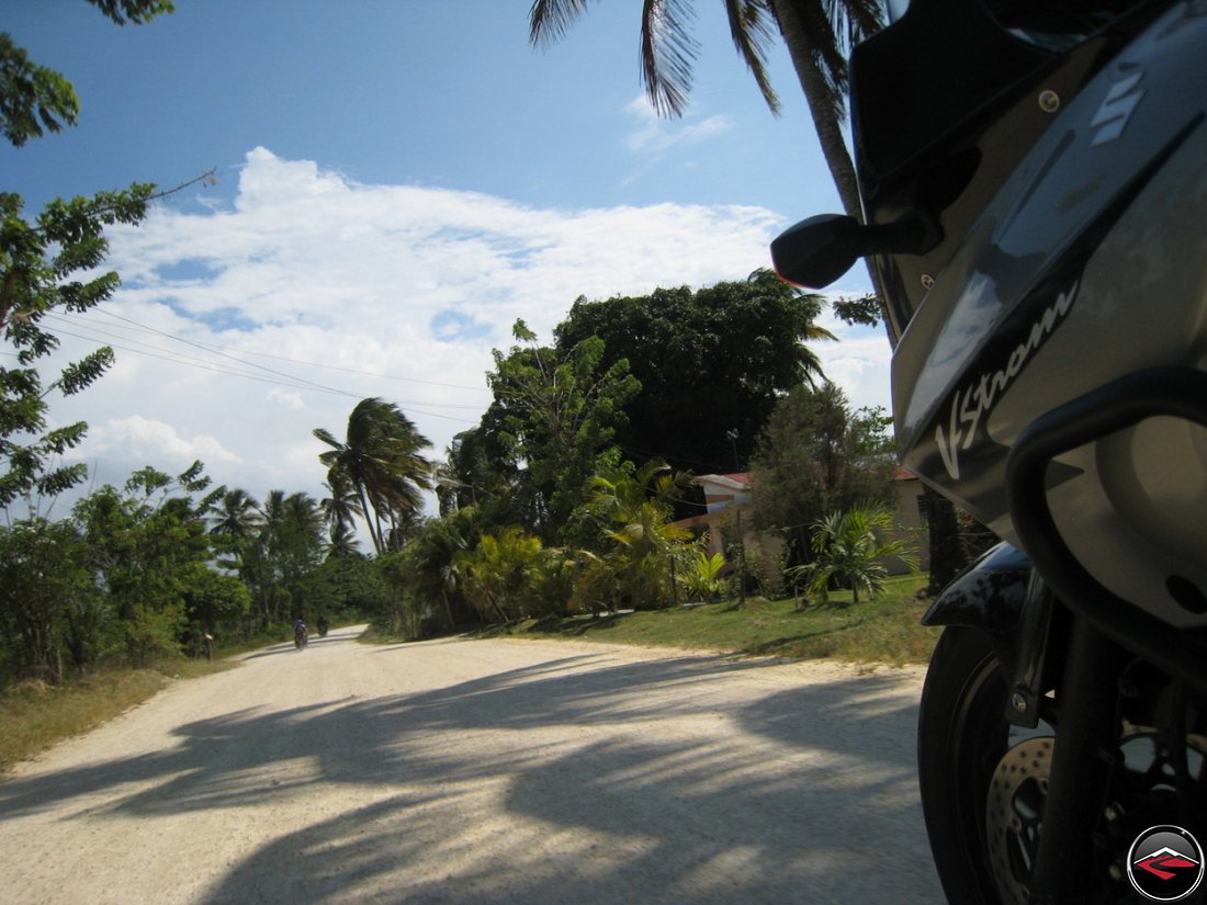 motorcycle riding down caribbean road with clouds over palm trees