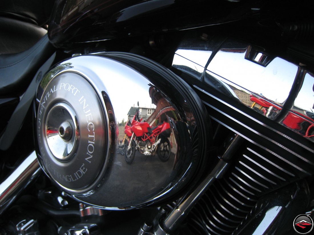 ducati motorcycles being reflected in the chrome of a harley-davidson air cleaner cover