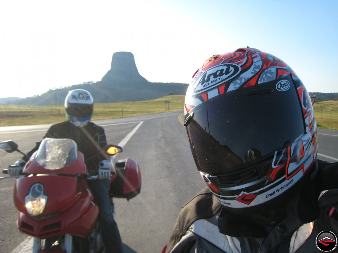 Two motorcyclists selfie with Devils Tower at Sunset behind them