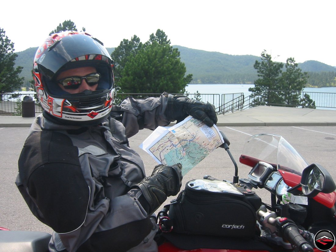 Motorcyclist wearing a full face helmet holding up a road map