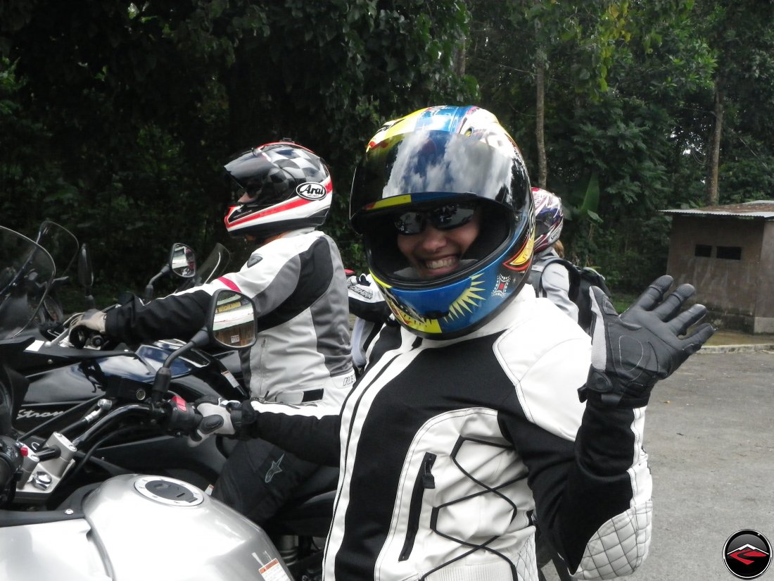 Kris, while riding her Suzuki V-Strom 650, Waves at the camera