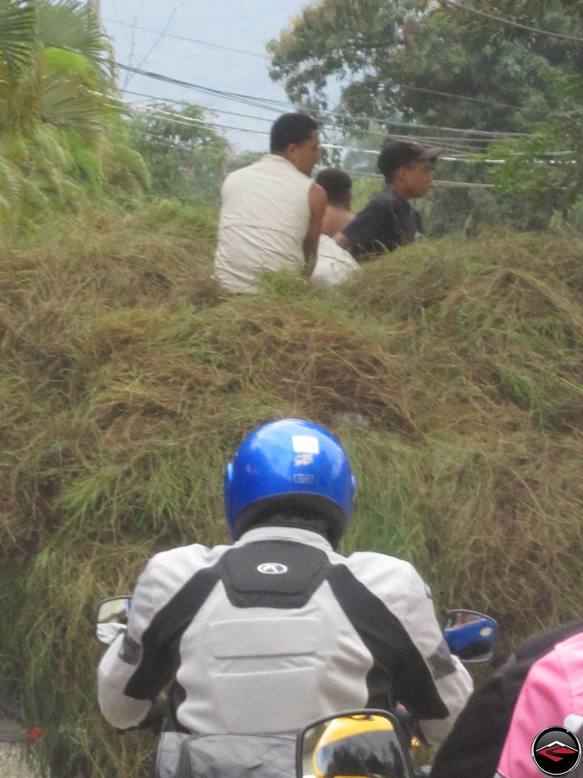 Motorcycle stuck behind a slow moving truck carrying grass