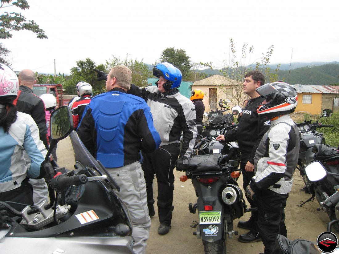 Group of motorcyclists look off into the distance while one man points