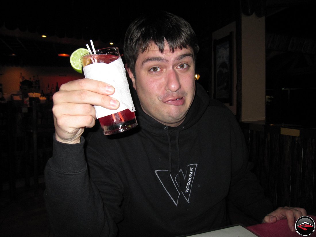 Man holding an alcoholic drink with a funny look on his face