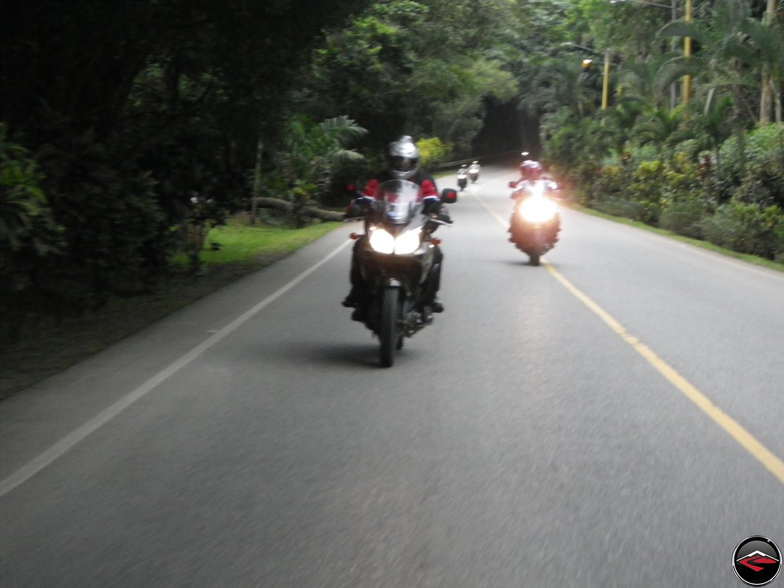 Riding Suzuki V-Strom 650 Motorcycles on highway 28 past dense caribbean island vegetation near La Vega Dominica Republic 