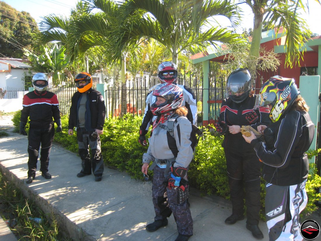 Motorcyclists standing on the sidewalk while wearing full gear in Moca Dominican Republic