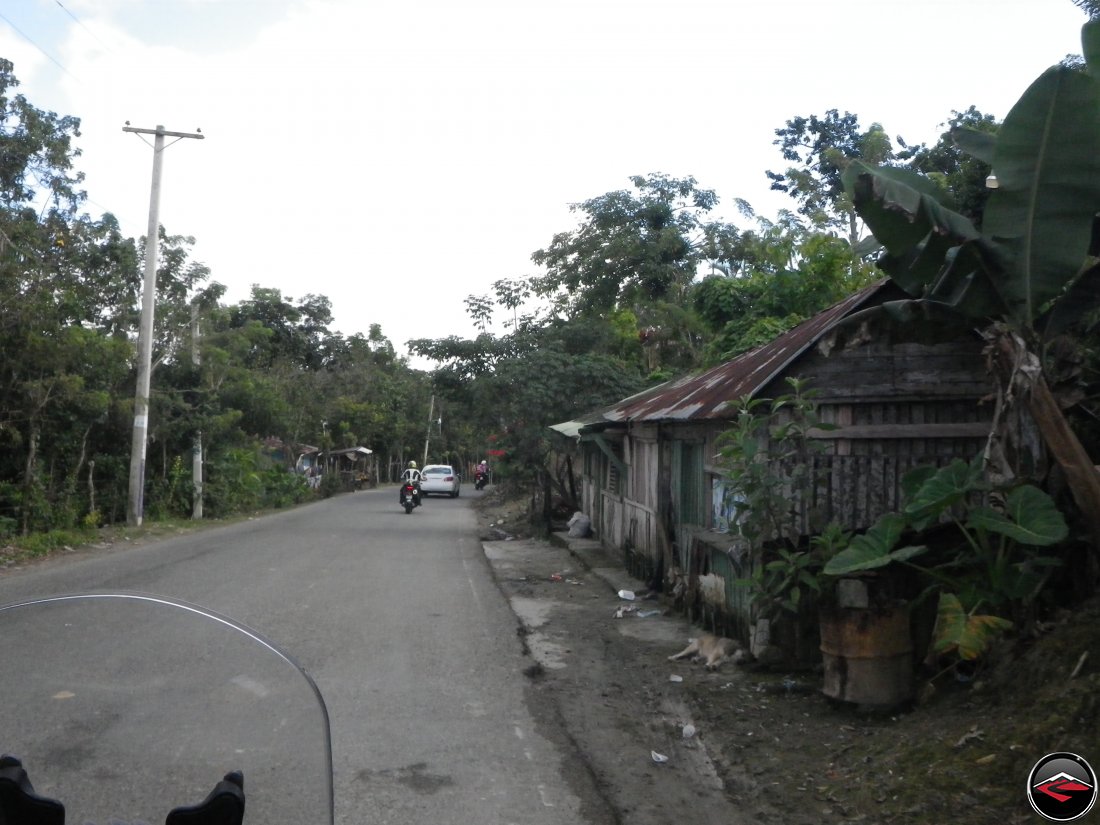 People living right next to the road, with a dog sleeping on the shoulder of highway 21 near Sabaneta de Yasica Dominican Republic