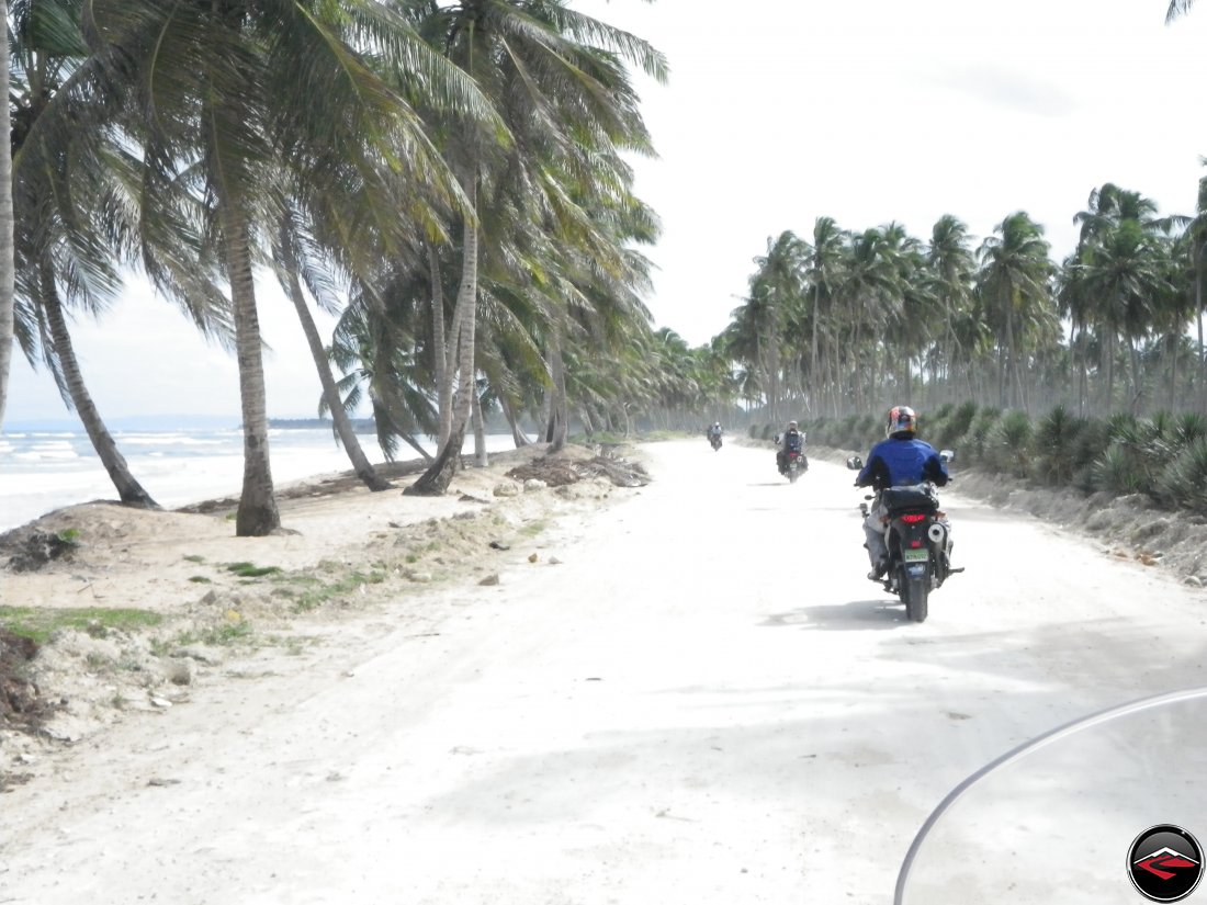 Riding motorcycles along the northern coastline of the Dominican Repblic with white sandy beaches and palm tree's blowing in the wind