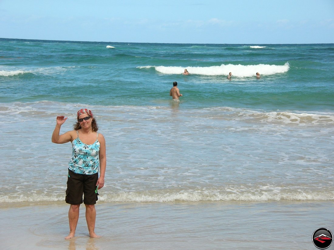 Woman standing on the beach while people play in the caribbean waters
