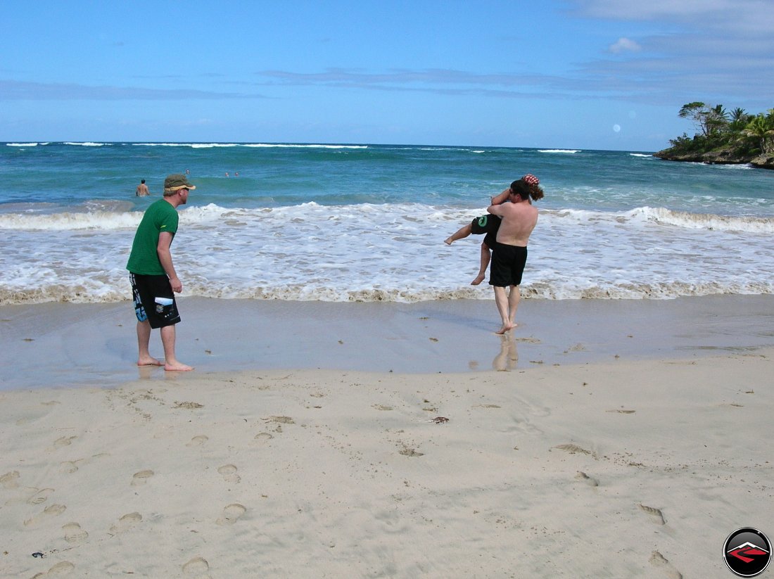 Man carrying woman into the water on the beach