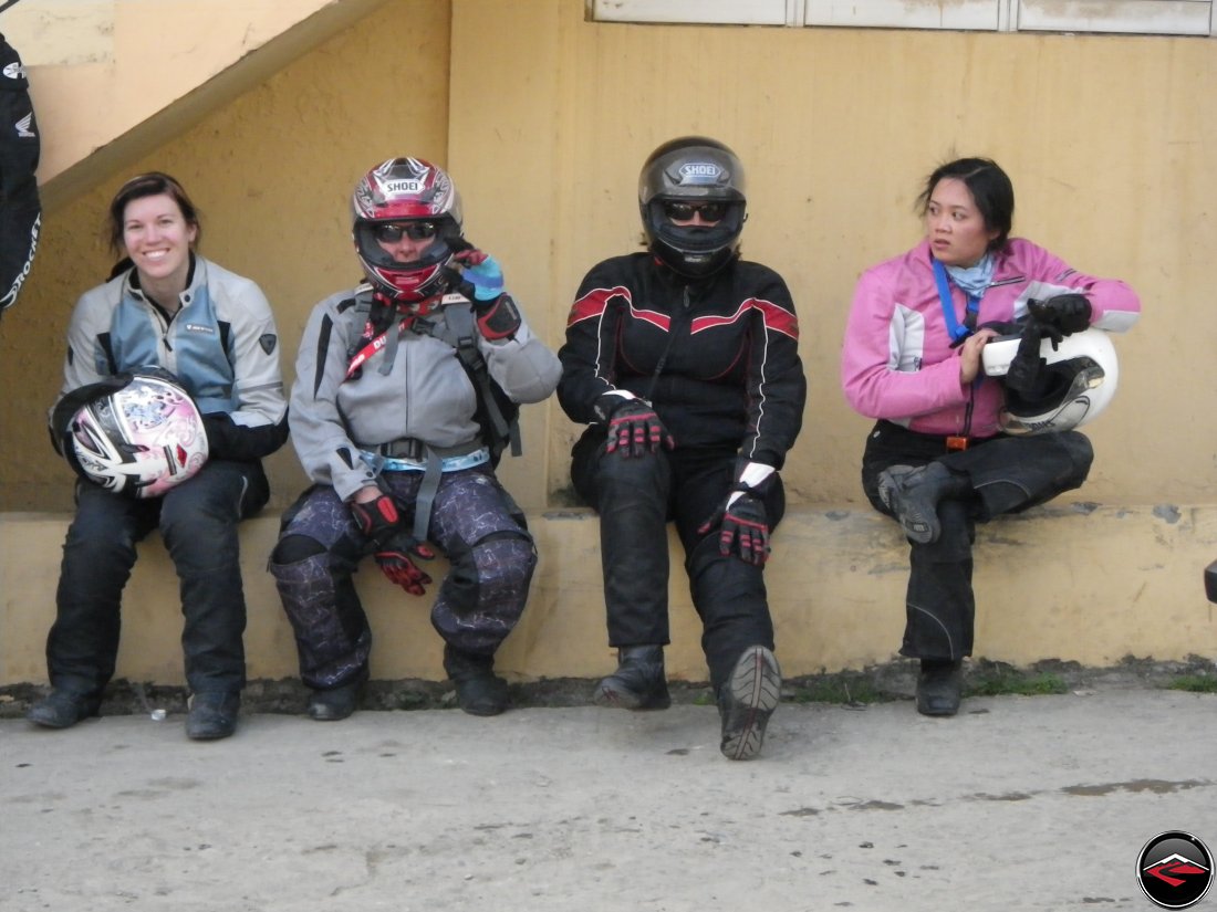 four motorcycle girls sitting on a wall