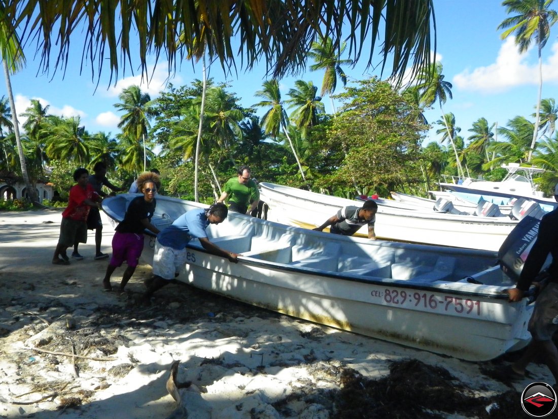 Eric helps Dominican Republic men push a boat off the beah and into the water