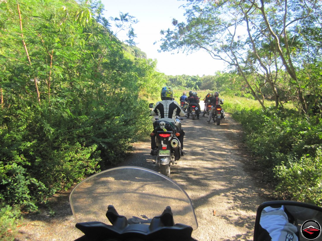 Group of motorcycles ride down a super narrow road through the jungle on a caribbean island