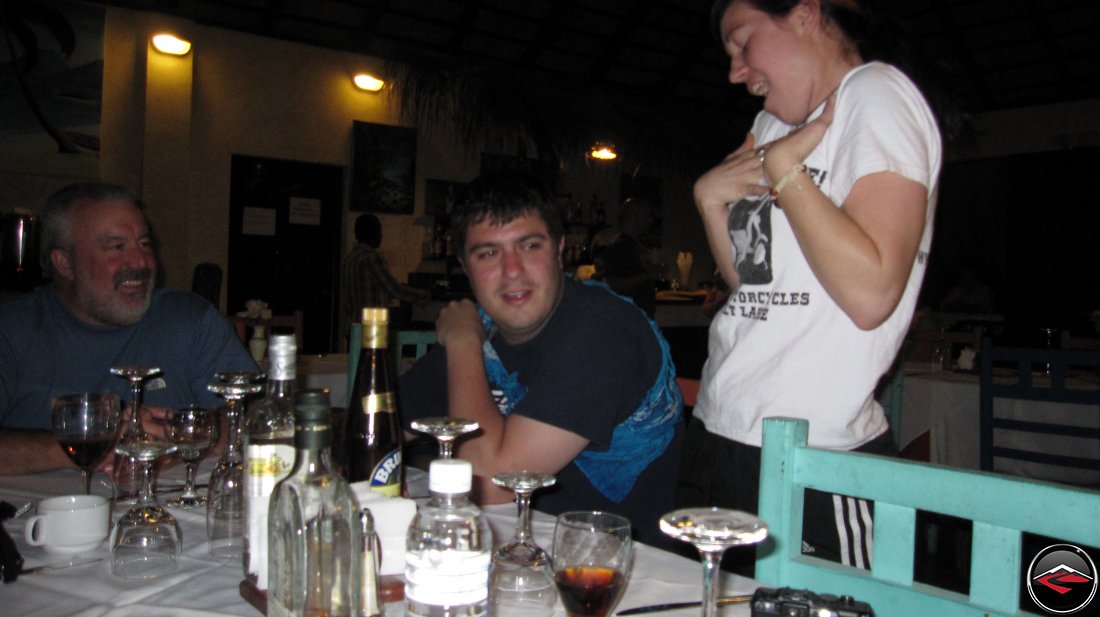 woman singing to a man sitting at a table to make him feel better La Tambora Beach Resort