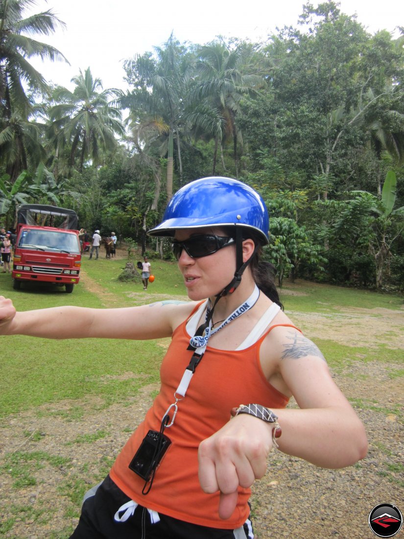 woman pretends to ride a chopper while wearing a silly helmet Cascada El Limon Dominican Republic