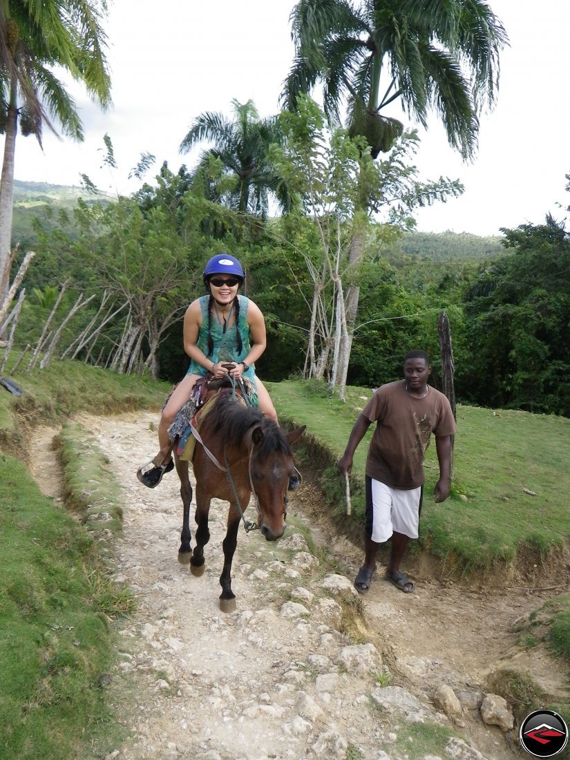 Woman riding a small horse on a caribbean island Cascada El Limon Dominican Republic