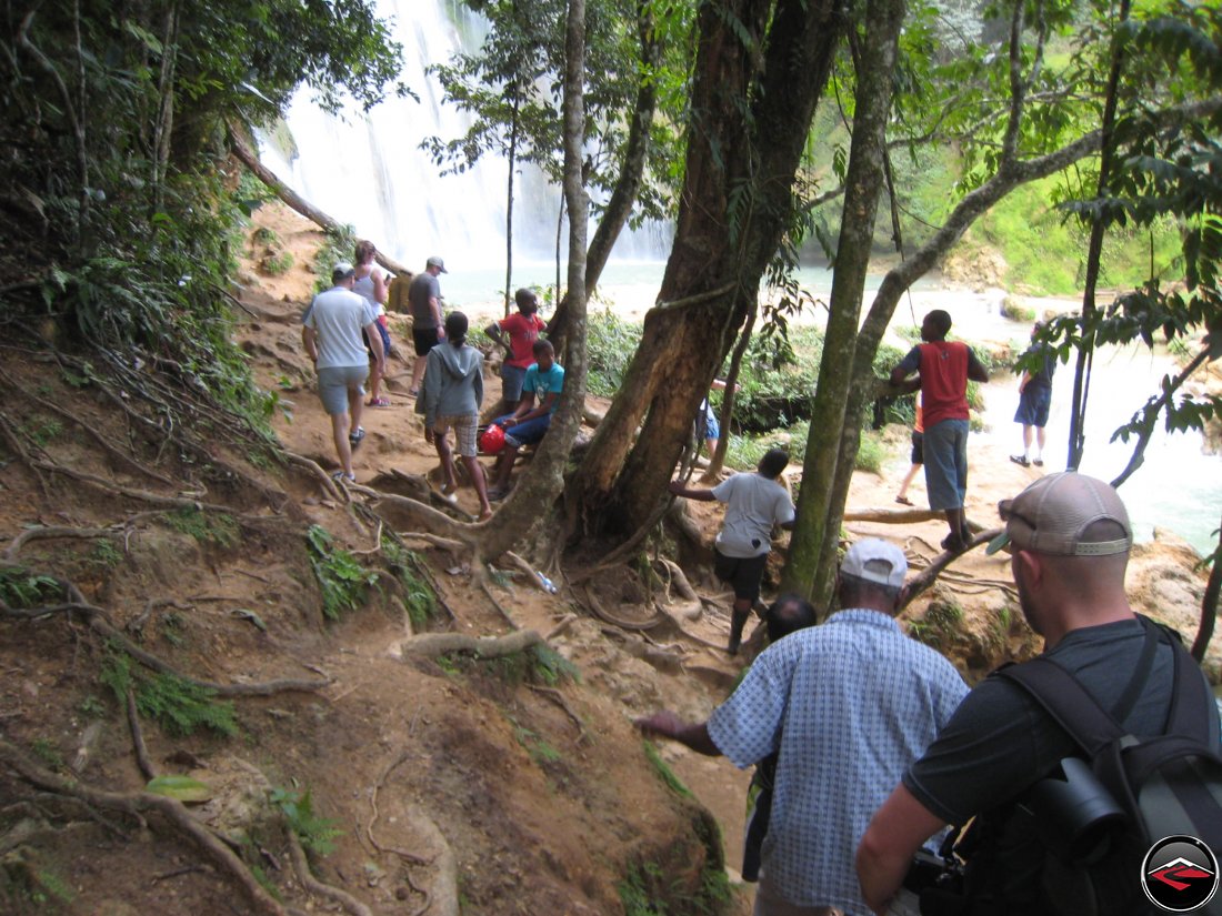 People hiking down a hill, approaching the bottom of the waterfall Cascada El Limon Dominican Republic