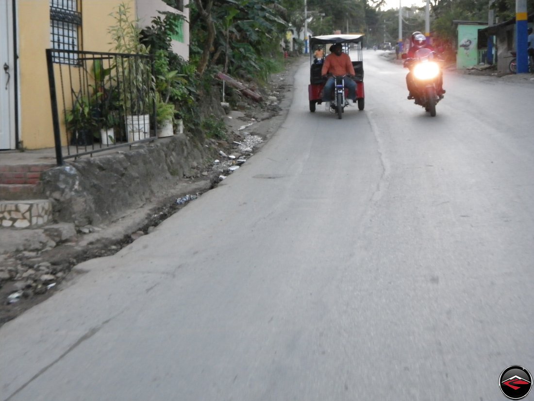 motorcycle passing a three-wheeled moto taxi on a caribbean island