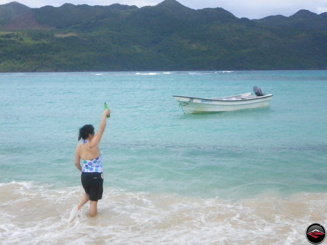 woman holding a presidente beer in the air on the beach Playa Rincon Dominican Republic