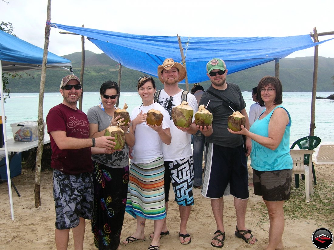 group of people standing on the beach holding pina colodas made out of coconut Playa Rincon Dominican Republics