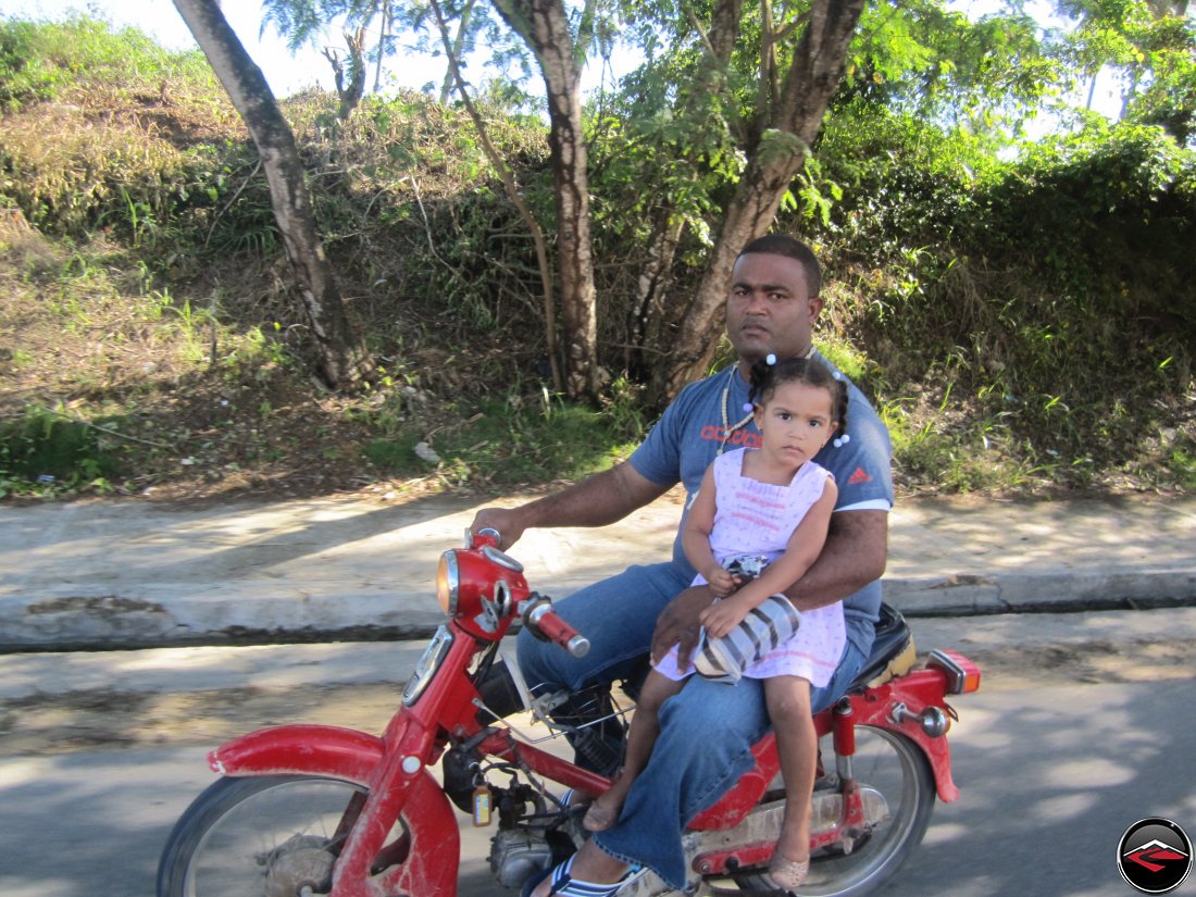 man riding a motorcycle with his daughter, a 3-year old girl, on his lap
