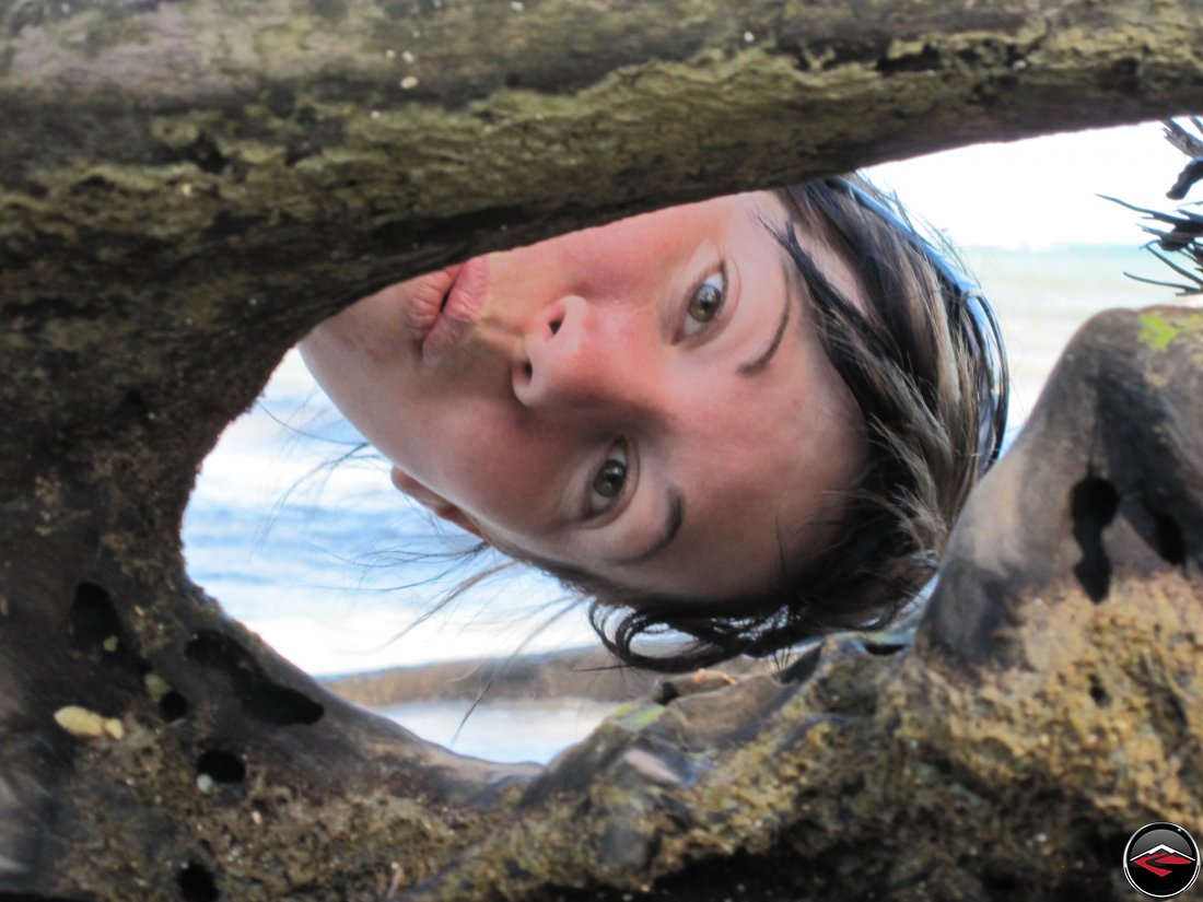 woman looking through a hole in a log