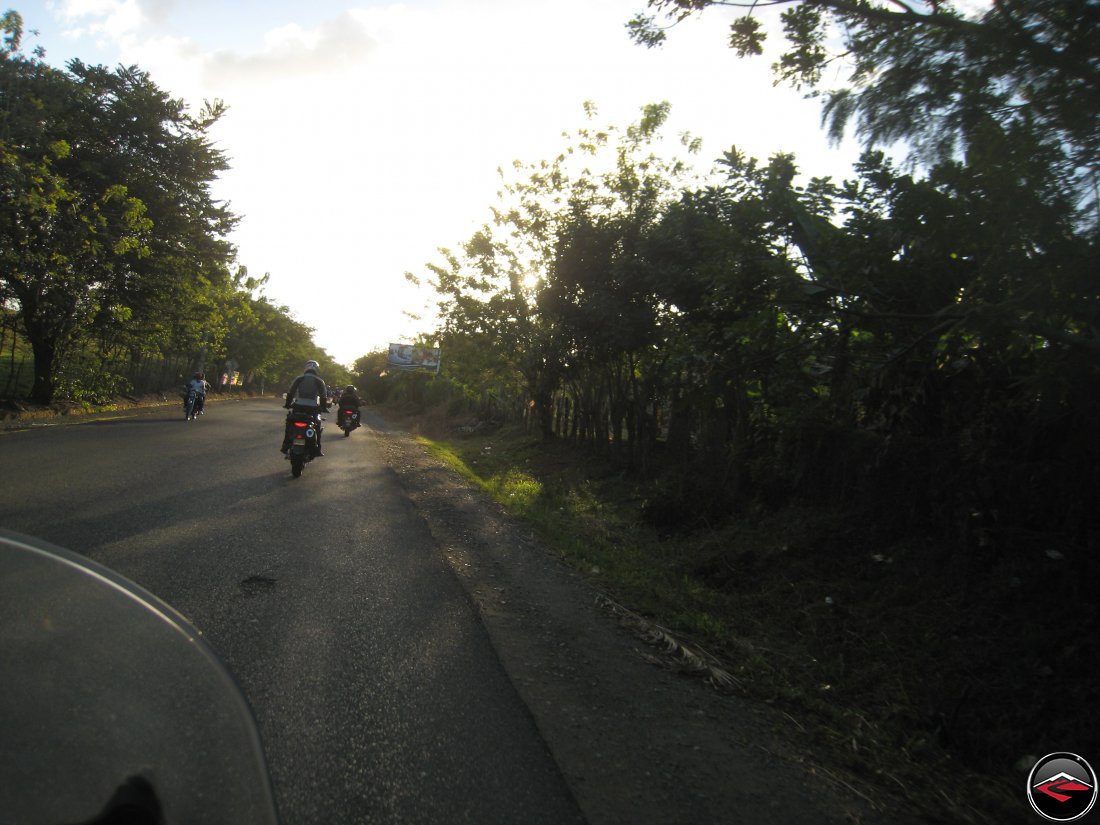 motorcycle riders stand up while riding into the sunset