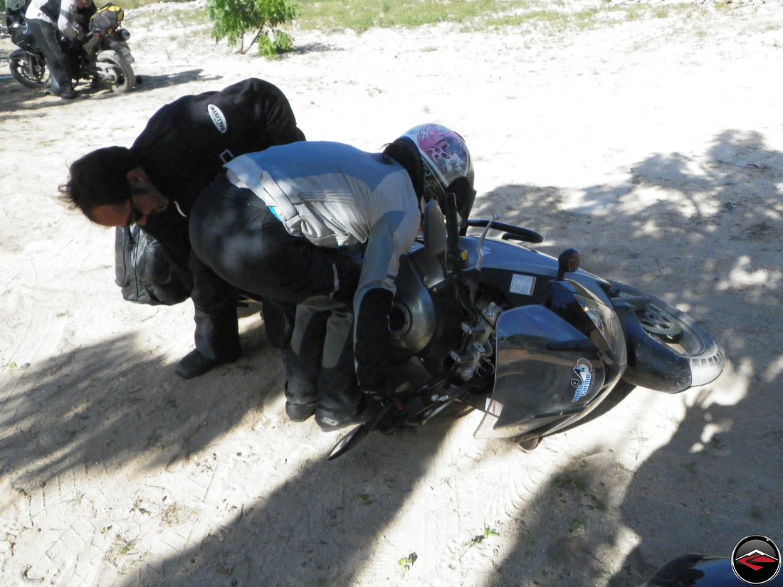 girl picking up a dropped motorcycle