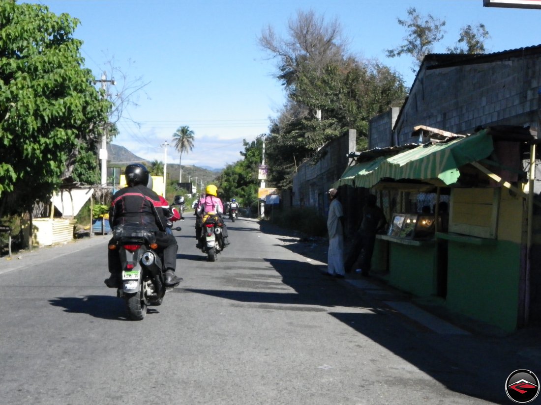 motorcycles riding past caribbean homes and businesses right off the side of the road