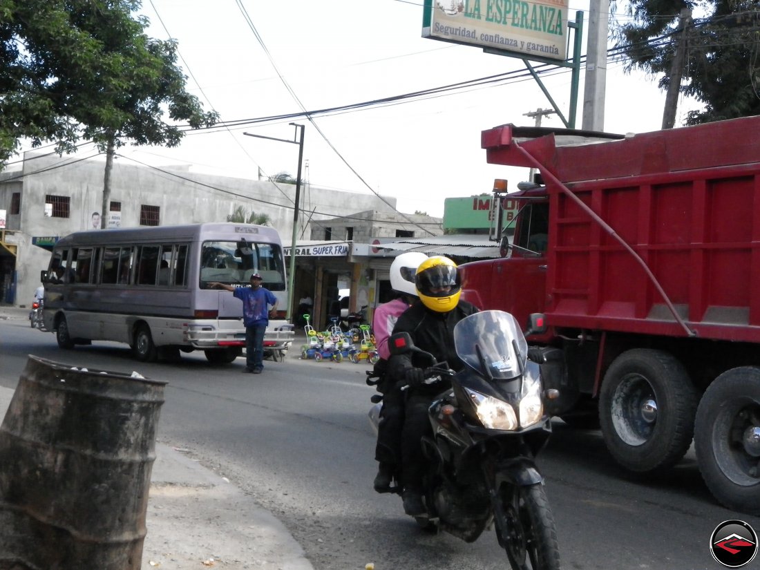 motorcycle riding around a city corner in the dominican republic, la esperanza, seguridad, confianza y garantia