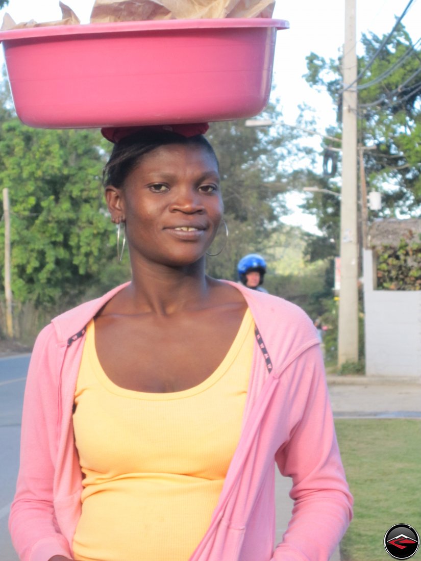 woman carrying heavy pink bucket on her head