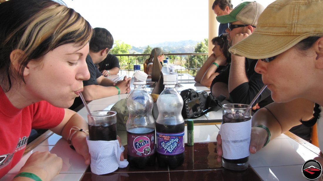 two pretty women drinking grape fanta soda through a straw