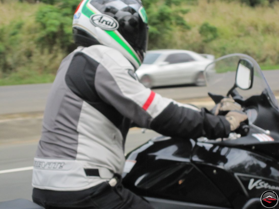 Man riding a motorcycle with one hand covering the kill-switch