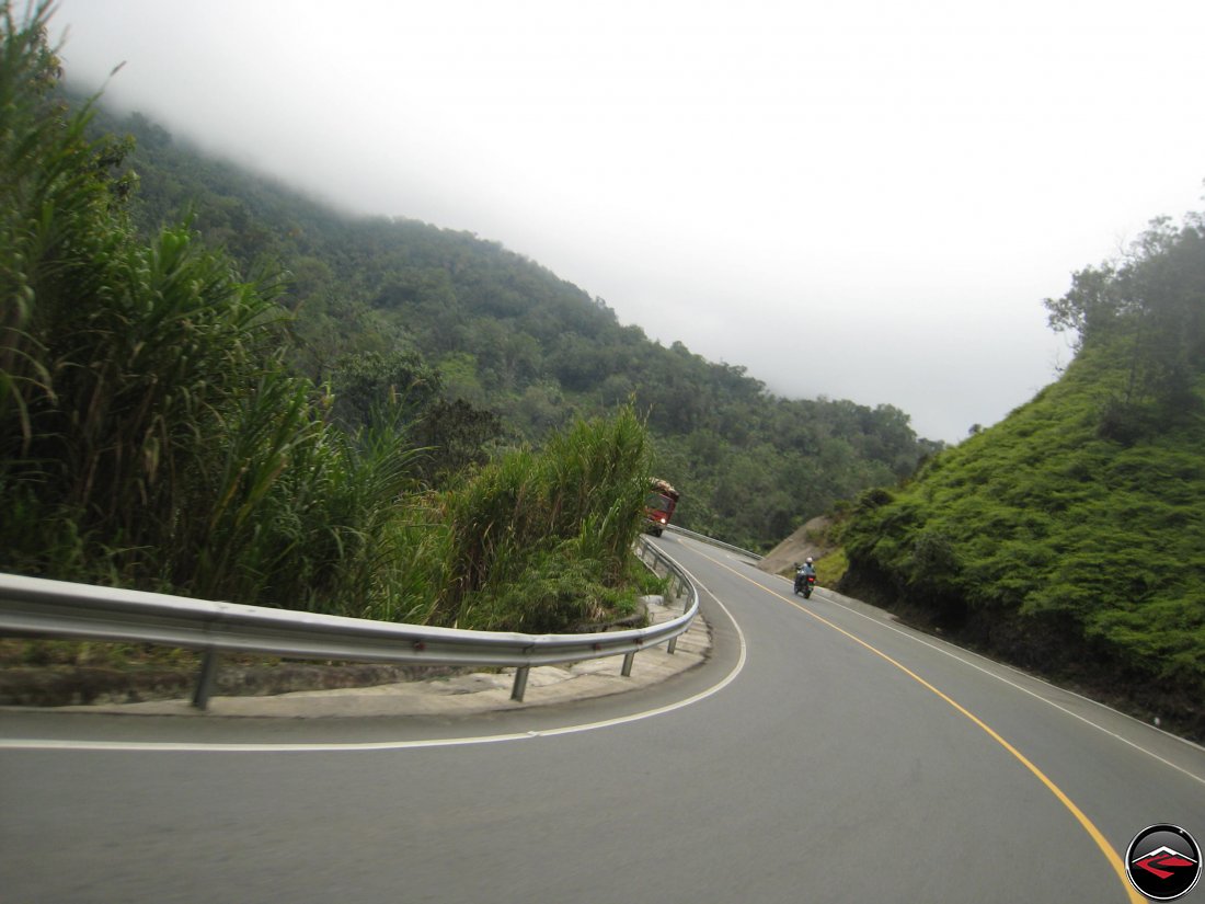 girl riding a motorcycle down a steep mountain road that drops to the valley floor