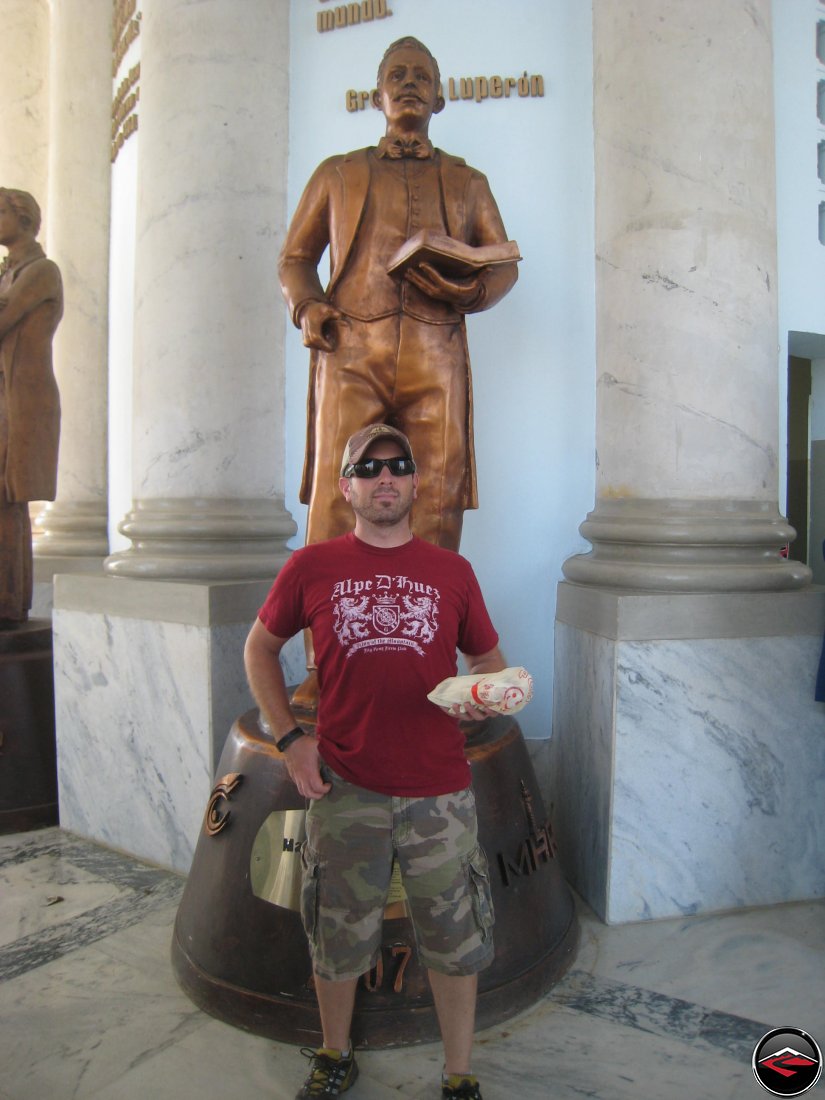 man mimicking copying the statue behind him holding a sandwhich