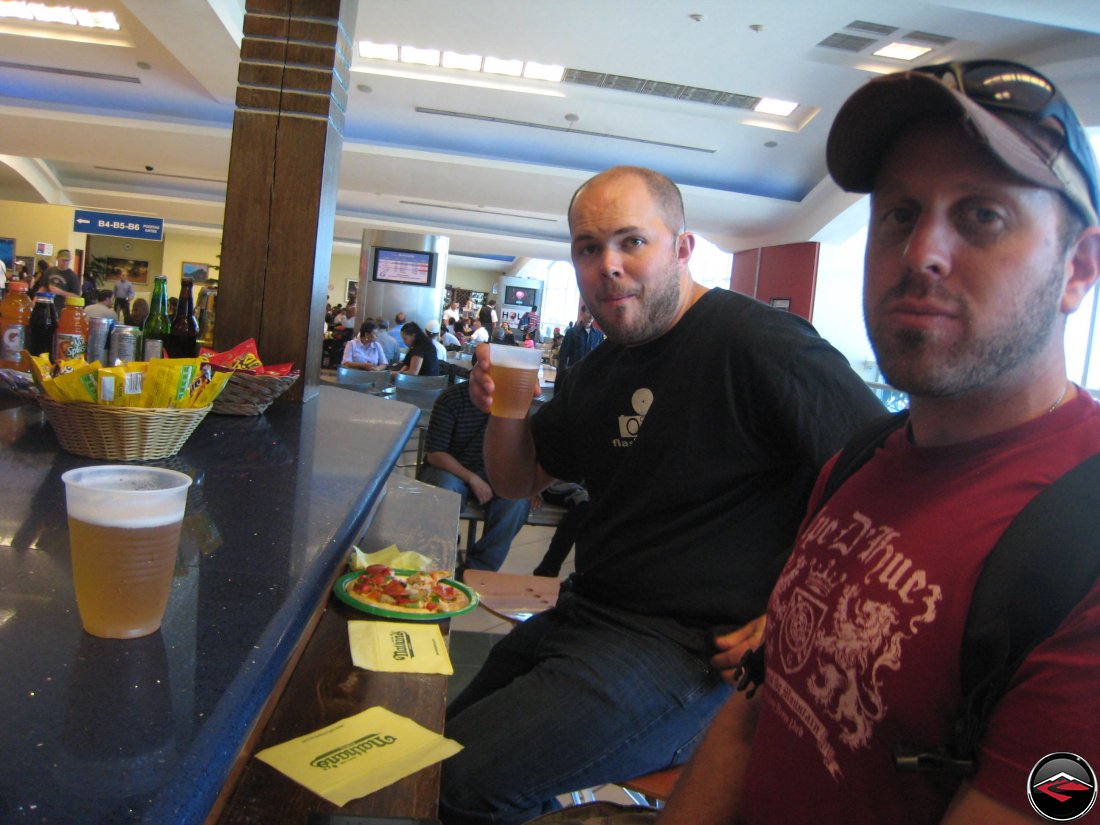 two men drinking beer at an airport
