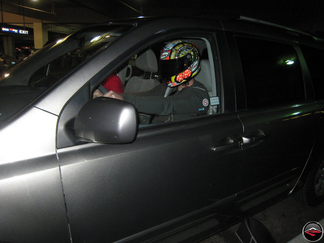 man wearing a helmet while driving a mini van, kind of like the stig