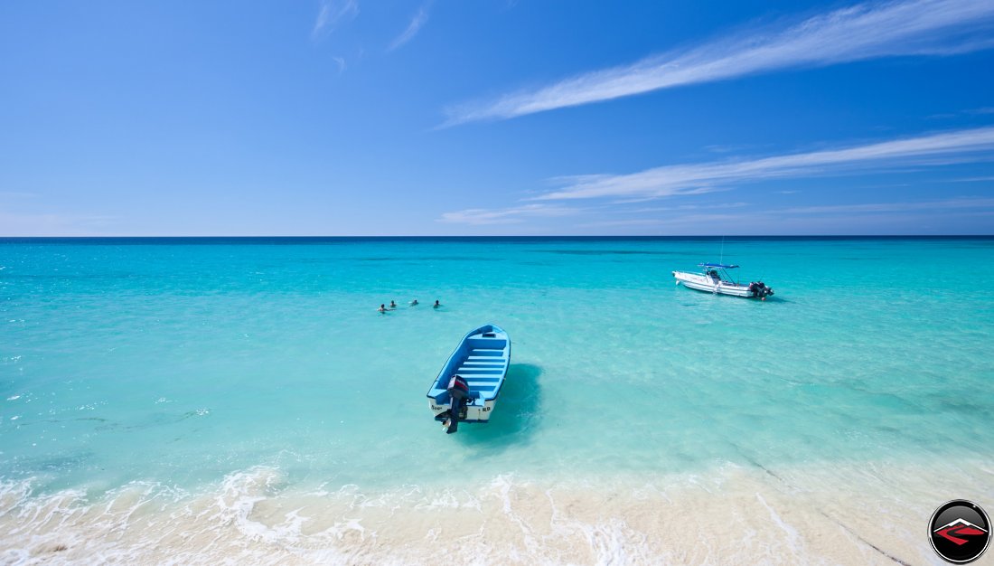 four people swimming in the perfect caribbean waters on a white sandy beach