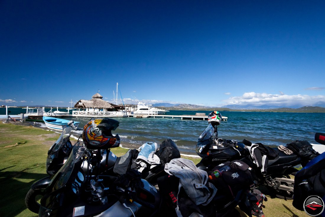 Motorcycles parked in the shade next to the ocean